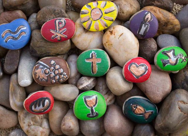 Steine, welche mit christlichen Symbolen wie einem Kreuz, einem Fisch oder einem Kelch bemalt sind.